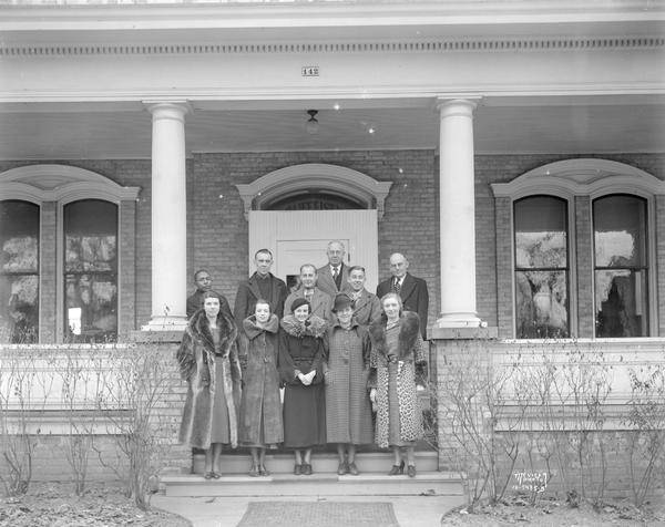 Eleven CUNA (Credit Union National Association) employees standing on the porch of their office at Raiffeisen House, 142 East Gilman Street.