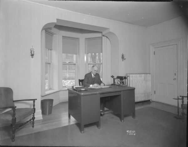 Earl Rentfro sitting behind his desk in his office at the Credit Union National Office, Raiffeisen House, 142 E. Gilman Street.