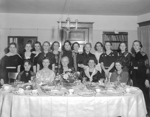 Group portrait of seventeen women posing behind a dinner table, 24 W. Mifflin Street. Taken for Laura Anderson.