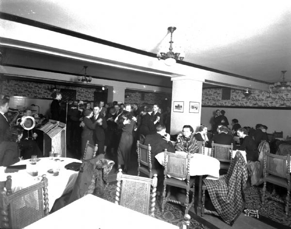 Couples dancing, eating and drinking in Club 22 at the Park Hotel. Also shows orchestra and singer.