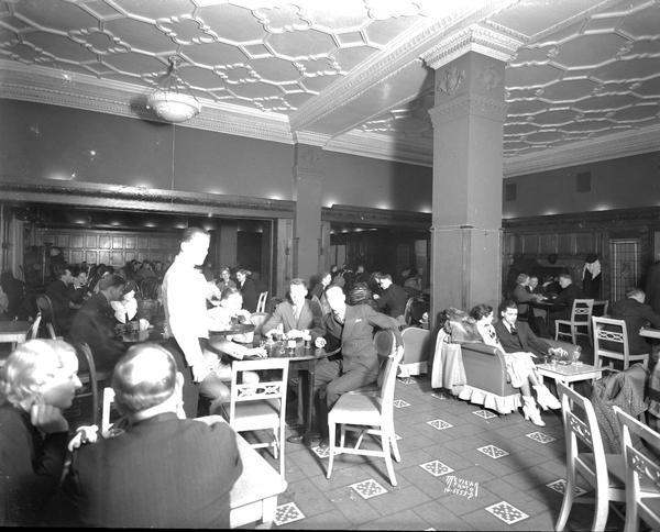 Men and women sitting at tables drinking in the Blue Room at the Park Hotel.