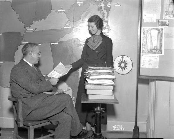 Woman handing 10,000th subscription to the C.U.N.A. (Credit Union National Association) "Bridge" to Mr. Roy F. Bergengren, managing director, who is sitting on the left.