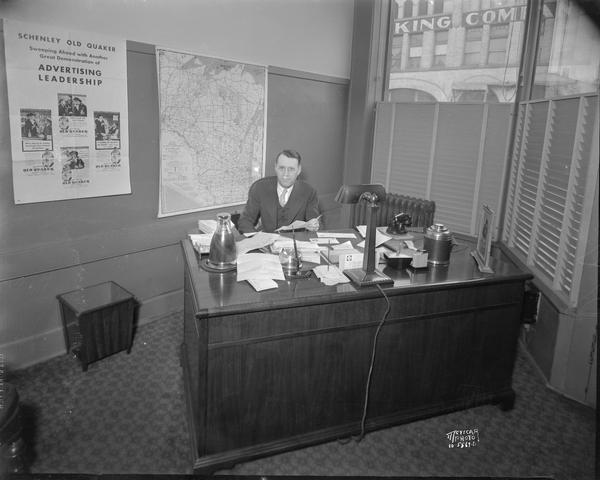 Jay Phillips in his private office, 220-222 East Main Street, with a Wisconsin map on the wall.