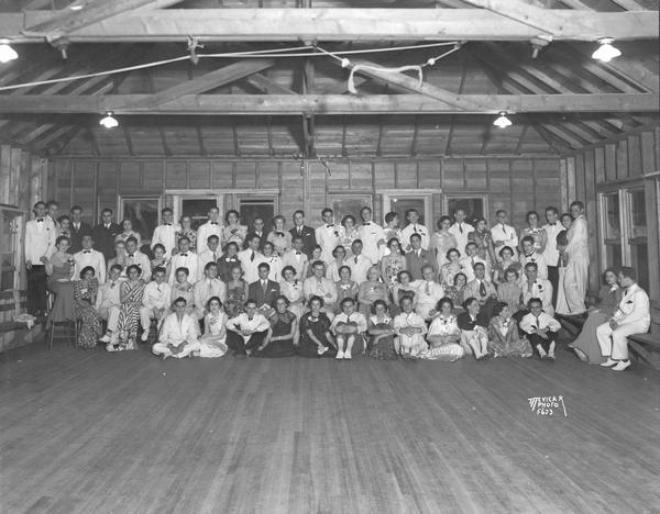 Group portrait of Alpha Epsilon Phi sorority with dates at spring formal in lodge building at Camp Indianola.