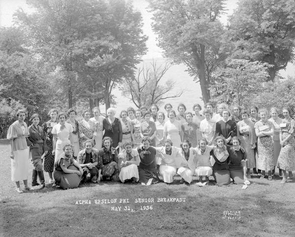Group portrait of Alpha Epsilon Phi sorority members taken on the lawn after the senior breakfast, 22 Langdon Street, with Lake Mendota in the background.