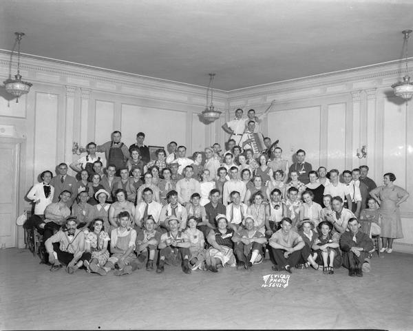 Group portrait of Kroger employees in costume at a Hard Times Party, Schenk's Hall, 2028 Atwood Avenue. There is a man with an accordion in the background.