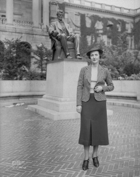 Woman model wearing checkerboard jacket, standing next to Lincoln Statue on Bascom Hill. For: Kessenich's.
