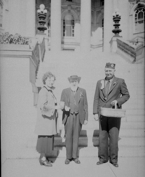 Charles W. Netherwood, Civil War veteran of Oregon, is shown buying the first Forget-me-not for the Disabled American Veterans' drive from Nina Westbury, past commander of the auxiliary and national chairman of the Americanization committee, with August Baumbach, senior vice commander, looking on.