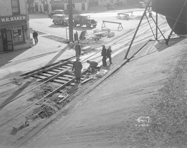 Elevated view of a construction crew working on Chicago & Northwestern Railroad crossing, showing the W.R. Baker Tavern at 601 E. Wilson Street, and the Paul A Genin Implement Co., 521 Williamson Street.