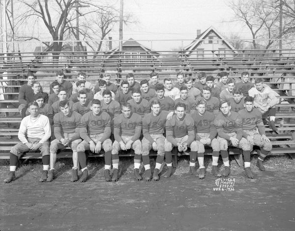 Group portrait of Central High School football team in uniform, sitting on bleachers.