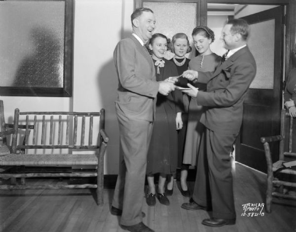 Roundy Coughlin buying ticket for President's Birthday Ball from a man, with three girls looking on.
