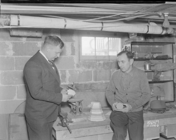 Harry C. Thompson, Madison recreation director and chairman of the Dane County WPA shut-in program, and Frank Buehler, 717 North Lawn Avenue, who has paralysis of both lower limbs, looking at blocks of wood Buehler made for Longfellow School crippled department, the first project that has been completed on the shut-in program.