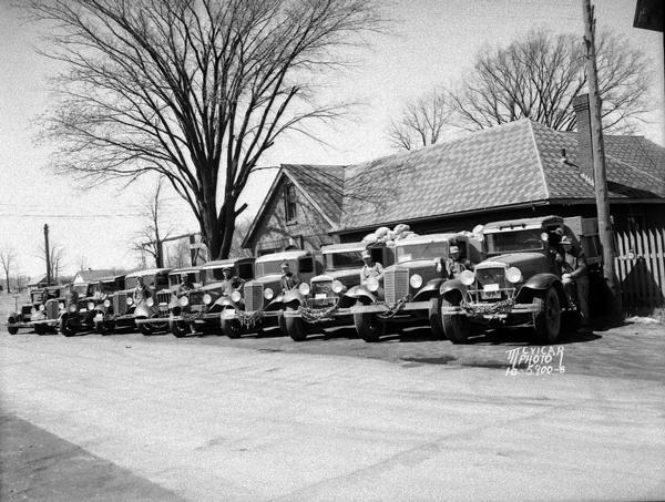 C.E. and P.A. Roth fleet of 10 trucks with drivers parked in front of their office, 2008 Roth Street (?).