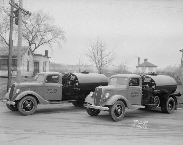 Two Taylor County tar tank trucks parked in front of Max Lehman's house, 1724 Park Street. Taken for William Gunnison, road contractor, Middleton, Wisconsin.