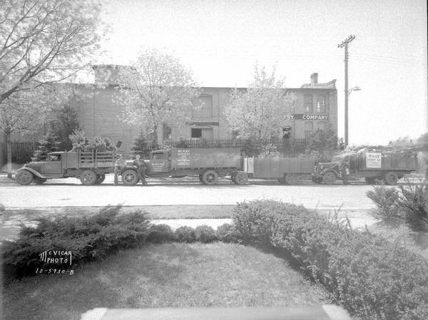 Three men and three trucks parked in front of McKay Nursery Co. building.