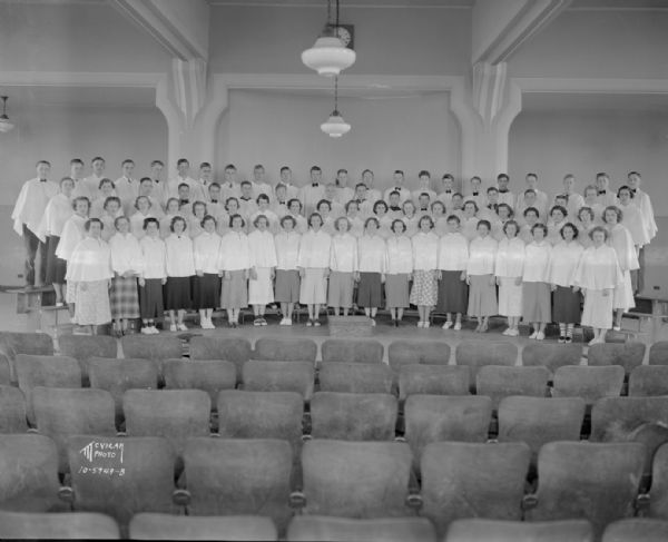 Group portrait of East High School a capella choir in costume standing on risers on a stage.