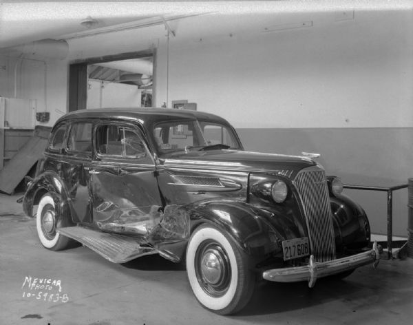 Three-quarter view from front left towards a wrecked Chevrolet car with Illinois license plate.