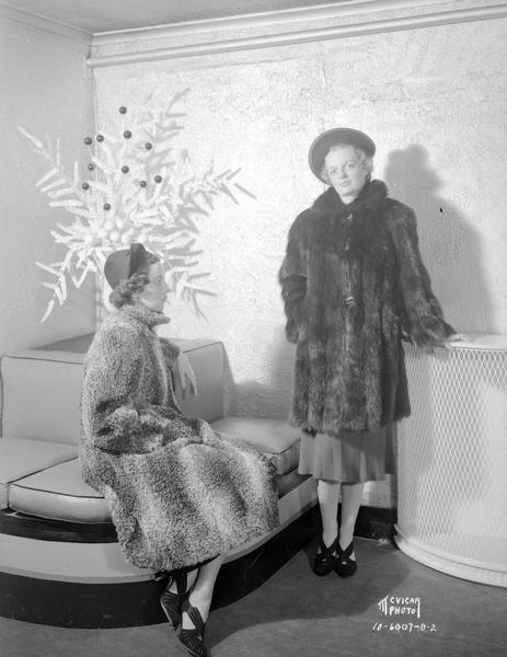 Two women modeling fur coats for Simpson's women's clothing store, 23 N. Pinckney Street. Alternate view.