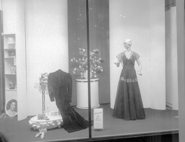 Window display at Baron Brothers Store, 12-18 W. Mifflin Street. Featuring a floor length coat, and a mannequin wearing a formal dress.