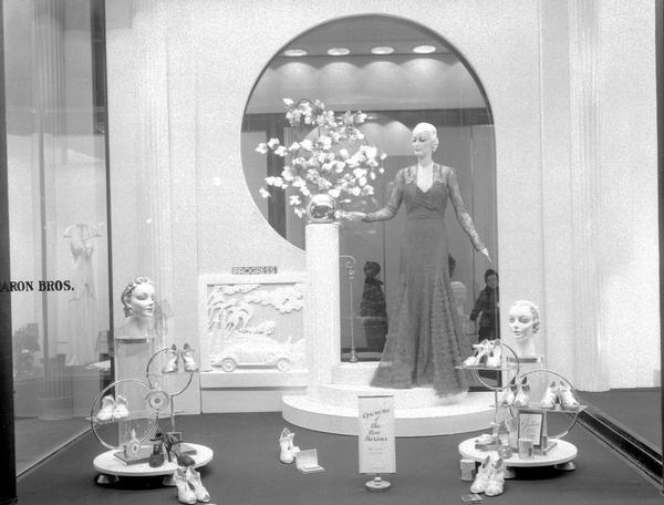 Window display at Baron Brothers Store, 12-18 W. Mifflin Street. Features a mannequin wearing a formal dress, and a shoe display.