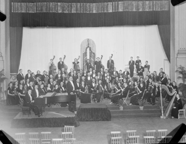 Elevated view of the Madison Civic Orchestra on stage in the Masonic Temple in concert dress with instruments.