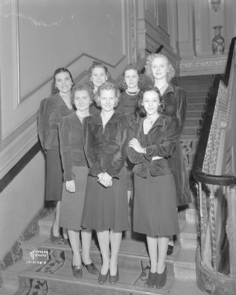 Group portrait of seven ticket girls in matching uniform tops at Orpheum Theater, 216 State Street.
