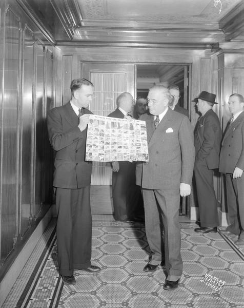 Cyril Ballam and Governor Julius P. Heil looking at a National Wildlife Restoration Week poster.