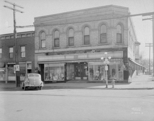 Fort Atkinson street corner showing automobile parked in front of Epert Dry Goods Co. Also shows lamppost and signs for Highways 12, 26 and 89.