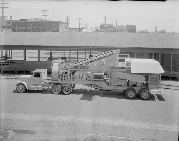 Elevated view of a truck-pulled rock crusher at Wisconsin Foundry & Machine Company, 623 East Main Street. In the background can be seen the International Harvester Company of America building, 301 South Blount Street.