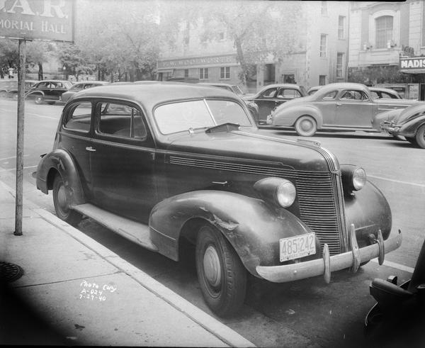 Attorney William A. Nathenson's Pontiac automobile with damaged right front fender parked in front of GAR Memorial Hall on Monona Avenue. The Madison Theater and Woolworths are across the street.