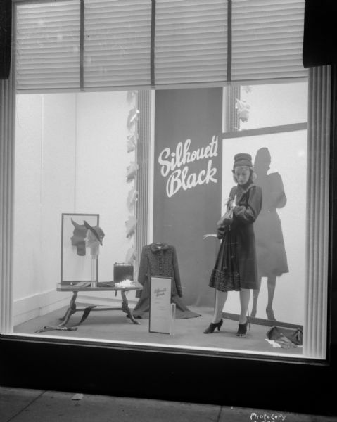 Manchester's, Inc., Department Store, 2-6 E. Mifflin Streeet, "Silhouette Black" window display, with mannequin in a coat with front fullness, and other outdoor dress items.