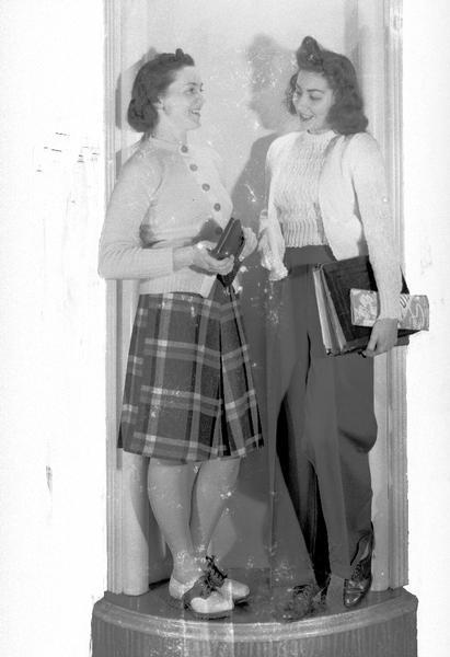 Darling Shop, 9 East Main Street, female clothing models, Beverly Muenchow and Eileen Regan, one wearing sports outfit with trousers and the other wearing sports outfit with skirt and blouse, and saddle shoes.