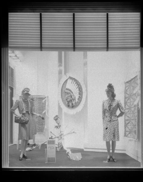 Display of women's fashions in a Manchester's, Inc., Department Store window, featuring "Indian Prints," fabrics with Native American designs.