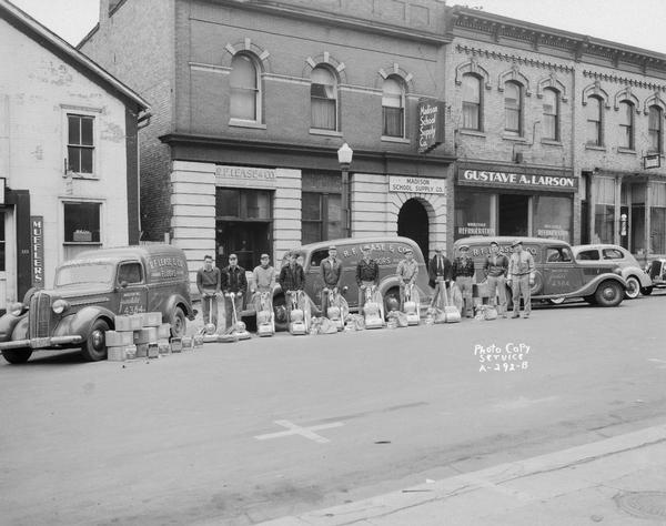 R.F. Lease and Co., 209 East Main Street, floor sanding company trucks, with eleven men standing beside their floor sanders. Other businesses in view: Madison School Supply, 207 East Main Street, Gustave Larson Refrigeration Supplies, 205 East Main Street.