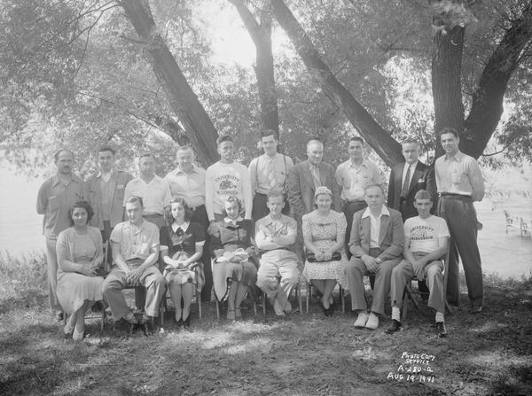 Group portrait of men and women taken outdoors at 225 Lake Lawn Place, Alpha Tau Omega Fraternity, taken for Jack McEhlone. Two men are wearing University of Wisconsin sweatshirts picturing a real badger.