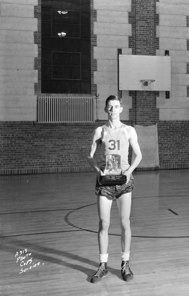 Edgewood High School male basketball player holding a trophy, "St. Norbert College Tournament, 1942, Bishop Rhode Award, 1st place."