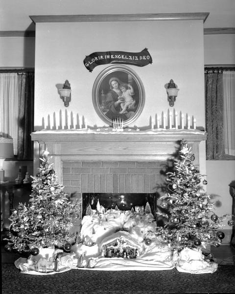 Fireplace featuring painting of Madonna and Child, creche, candles and two small Christmas trees.
