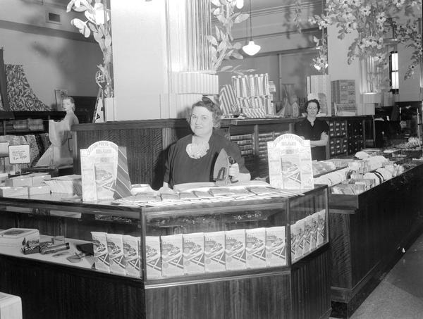 Woman holding iron and demonstrating the Pres Kloth (a pressing cloth) in Manchester's Department store, 2-6 East Mifflin Street.