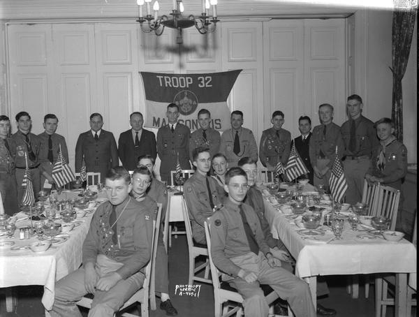 Boy Scouts, Troop #32 from Latter Day Saints Church, banquet with Senior Patrol scouts sitting at tables, and more scouts and adult leaders standing in the background. Farewell dinner for Chief James H. Gelwicks, Scout Executive, taken at the Madison Club.