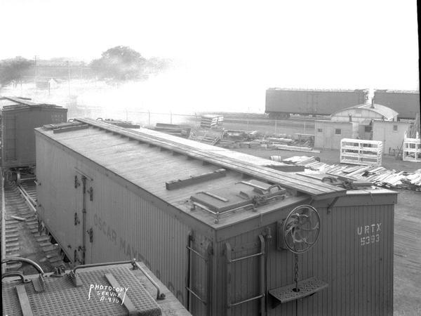 Elevated view of an Oscar Mayer refrigerated railroad car on the Chicago & Northwestern Railway, car number URTX 5393. The Oscar Mayer rail yard is in the background.