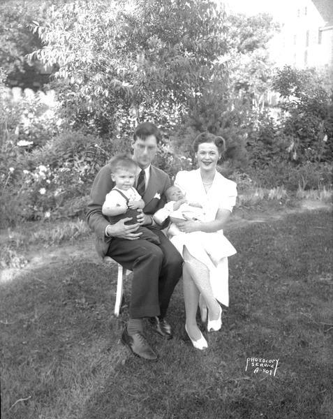 Group portrait of Thomas H. and Eileen Flad with their children, Joseph T. and Mary E., sitting in the yard.