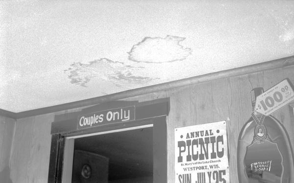 Interior view of ceiling of Dobby's Cosmo Club, owned by John C. Dobson, Route 1, Mendota Wisconsin, showing water damage. Sign over the door says "Couples only" and poster on the wall says "Annual Picnic, St. Mary's of the Lake Church, Westport Wis., Sun. July 25."