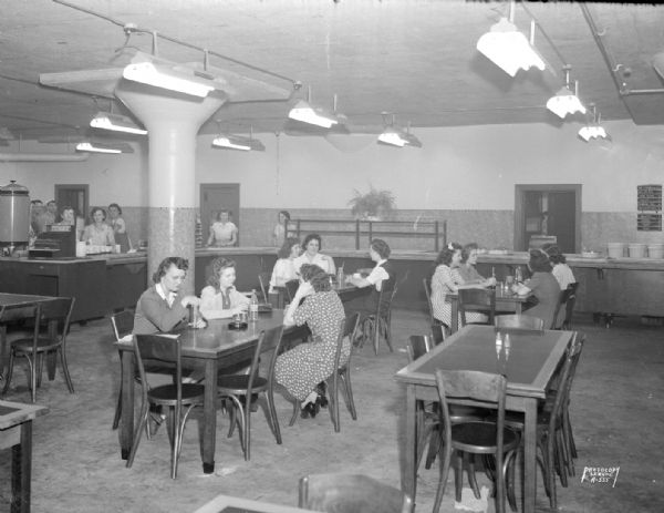 Oscar Mayer Company cafeteria, showing counter in the background, and women sitting at tables in the foreground.