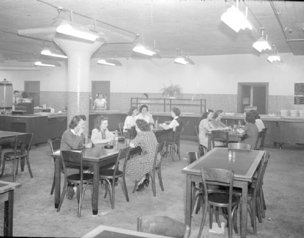 Oscar Mayer Company cafeteria showing counter in the background, and women sitting at tables in the foreground.