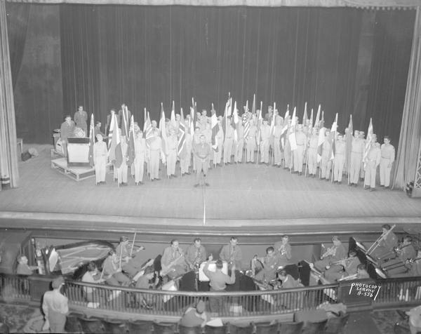 Elevated view of a scene from Truax Field's "Wac-Khaki" GI Revue: "We Are the United Nations" finale with chorus on stage holding international flags.