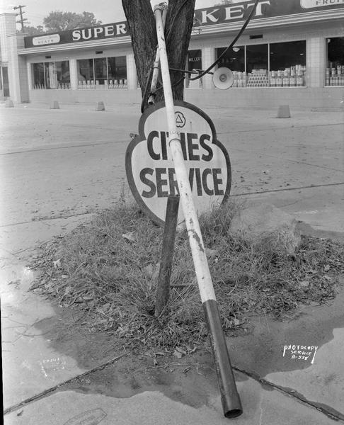 Broken sign for Cities Service Station, 2408 University Avenue. Millers' Super Market, at 2418 University Avenue, is in the background.