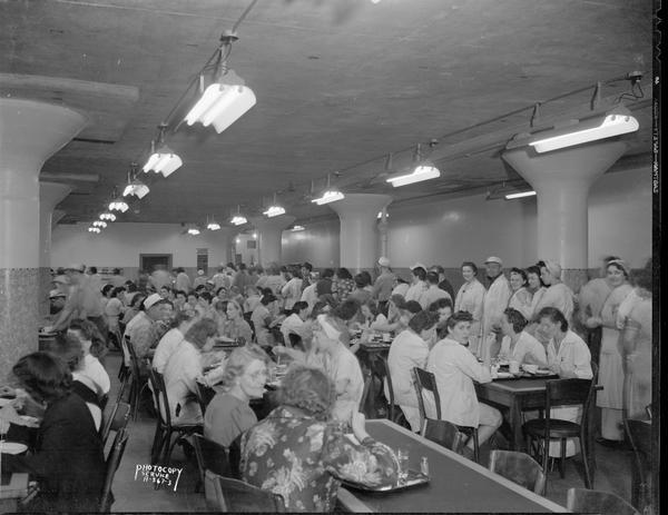 Oscar Mayer Company cafeteria showing men and women workers in line for food, and sitting at tables.