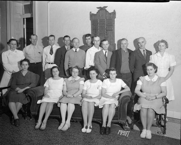 Group portrait of 9 men and 8 women employees (members of AFSCME Local 13 ?) in front of World War II Service plaque.