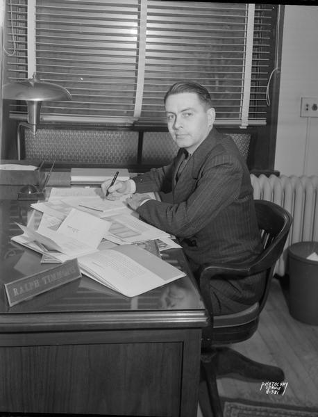 Ralph Timmons, president of Ralph Timmons Advertising Agency, 1. South Pinckney Street, seated at his desk.
