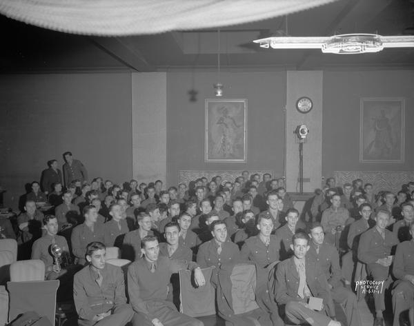 Large group of 628th Squadron men, in uniform, sitting at the Legion Club, 110-112 East Wilson Street, for a party.